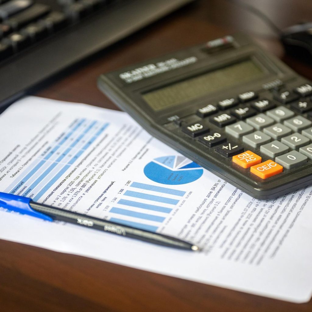 Calcolatrice e report finanziario sulla scrivania per il calcolo del costo di un dipendente
